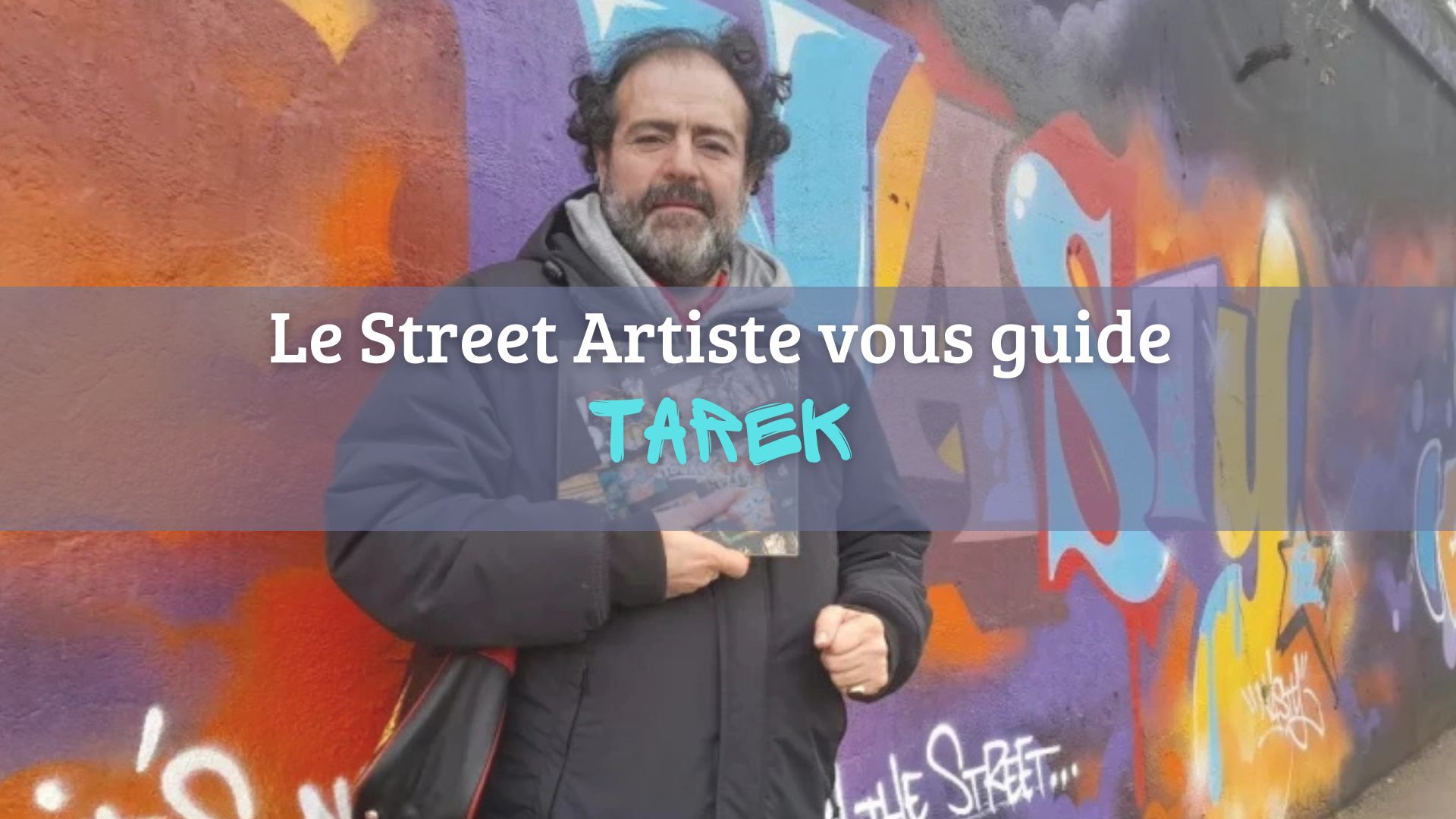 L'artiste Tarek devant une oeuvre de street art avec son livre Paris Tonkar en main